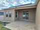 Covered patio with windows and sliding glass door, stone tile and green space at 625 Disa Dr, Davenport, FL 33837