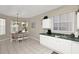 Open kitchen view with tile flooring, dining table, and white cabinets; brightened by natural light from windows with vertical blinds at 662 Orista Dr, Davenport, FL 33897