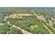Aerial view of a rural home nestled amongst dense trees with farmland and railroad nearby at 6925 3Rd St, Mulberry, FL 33860