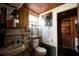 A small bathroom with a toilet, sink, mirror, and shelving awaits renovation at 6925 3Rd St, Mulberry, FL 33860