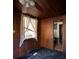 This bedroom with wood paneling awaits renovation with a window and a ceiling fan at 6925 3Rd St, Mulberry, FL 33860