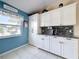 Kitchen with white cabinets, granite counters, modern backsplash and blue accent wall at 716 Maderia Ct, Kissimmee, FL 34758