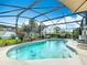 Sparkling screened-in pool area with lush landscaping, patio furniture, and sunny sky above at 716 Maderia Ct, Kissimmee, FL 34758