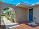 Welcoming front entrance with a vibrant blue door, textured walls, and beautiful landscaping at 9019 Oakwood Dr, Lake Wales, FL 33898