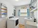 Well-equipped laundry room featuring a washer, dryer, utility sink, shelving, and a window for natural light at 9019 Oakwood Dr, Lake Wales, FL 33898