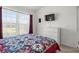Comfortable bedroom with large bright window, TV, white dresser, and a colorful quilt on the bed at 936 Lake Berkley Dr, Kissimmee, FL 34746