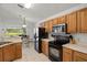 Spacious kitchen with wood cabinetry, stainless steel microwave, and black appliances overlooking a serene lake at 936 Lake Berkley Dr, Kissimmee, FL 34746