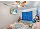 Charming bedroom with a ceiling fan and window with blue patterned curtains at 102 Deen Blvd, Auburndale, FL 33823