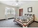 Sunlit bedroom with a window, patterned carpet, a comfortable bed with a quilt, and ceiling fan at 1024 Campbell Ave, Lake Wales, FL 33853