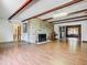 Open-concept living room with hardwood floors, a stone fireplace, exposed beams, and access to other rooms at 1024 Campbell Ave, Lake Wales, FL 33853