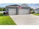 Well-maintained home showcasing a spacious driveway leading to a three-car garage with stone accents at 1045 Montgomery Ln, Polk City, FL 33868