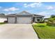 Beautiful single-story home featuring a three-car garage, an American flag, and manicured landscaping at 1045 Montgomery Ln, Polk City, FL 33868