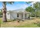 Rear exterior view featuring a covered patio area, a tidy yard, and mature trees in the background at 1103 W Dixie Ave, Plant City, FL 33563