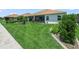 Manicured backyard with tropical trees and patio with ceiling fans and view of neutral colored home at 1104 Sawgrass Dr, Winter Haven, FL 33884