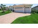 Well-manicured home featuring a three-car garage and brick paver driveway at 1104 Sawgrass Dr, Winter Haven, FL 33884