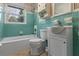 This bathroom has vintage blue tile, white fixtures, and a window with a view to the outdoors at 1371 Sheridan Sw St, Winter Haven, FL 33880