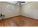 An empty bedroom displays hardwood floors, two windows, a ceiling fan, and fresh neutral paint at 1371 Sheridan Sw St, Winter Haven, FL 33880