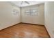 An empty bedroom displays hardwood floors, two windows, a ceiling fan, and neutral paint at 1371 Sheridan Sw St, Winter Haven, FL 33880