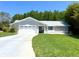 Well-maintained home with a two-car garage, manicured lawn, and verdant trees offering curb appeal at 14 Cypress Run, Haines City, FL 33844