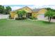 Inviting yellow home with manicured lawn, palm trees, and a charming entrance at 147 Brookshire Dr, Lake Wales, FL 33898