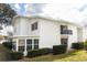 White condo featuring a screened patio, a small balcony and manicured landscaping at 1550 11Th Ne St # E7, Winter Haven, FL 33881