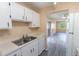 Efficient kitchen features stainless steel sink, white cabinets, and neutral countertops, flowing into the living area at 1550 11Th Ne St # E7, Winter Haven, FL 33881