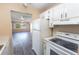 View from kitchen showing white appliances, wood-look floors, and living room at 1550 11Th Ne St # E7, Winter Haven, FL 33881