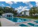 Community pool surrounded by palm trees, a pool house, and lush greenery at 1550 11Th Ne St # E7, Winter Haven, FL 33881