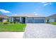 Charming single-story home with a well-manicured lawn, paver driveway, and a two-car garage under a clear blue sky at 157 Walkers Point Dr, Auburndale, FL 33823