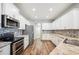 Modern kitchen featuring stainless steel appliances, white cabinets, and stylish backsplash and wood flooring at 157 Walkers Point Dr, Auburndale, FL 33823