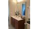 Bathroom featuring wood cabinets, modern fixtures, decorative mirror, and neutral walls at 1820 Coriander Dr, Poinciana, FL 34759