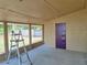 Screened porch with an unfinished ceiling and a violet door at 1919 19Th Nw St, Winter Haven, FL 33881
