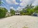 Exterior view of the home featuring a gravel driveway, lush greenery, and a well-maintained yard at 2222 12Th Nw St, Winter Haven, FL 33881