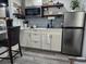 Charming kitchenette with stainless steel refrigerator, white cabinets, open wood shelving, and unique backsplash at 2222 12Th Nw St, Winter Haven, FL 33881
