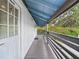 Covered outdoor walkway with gray wood railing, white walls, and a painted blue ceiling at 2222 12Th Nw St, Winter Haven, FL 33881