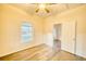 Bright bedroom with wood-look floors, ceiling fan, closet with mirrored doors, and open doorway to another room at 230 Denton Ave, Auburndale, FL 33823