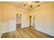 Bright bedroom with wood-look floors, ceiling fan, closet with mirrored doors, and open doorway to another room at 230 Denton Ave, Auburndale, FL 33823