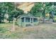 Charming, light-green cottage-style home with a screened-in porch, surrounded by mature trees and a cloudy sky at 230 Denton Ave, Auburndale, FL 33823