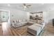 Bright and airy living room featuring hardwood floors and a large sectional sofa, with an open view to the kitchen at 2356 Palm Park Loop, Clermont, FL 34714