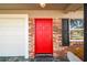 This front door has a bright red finish and brick facade surrounded by a white garage door at 2640 Handley Blvd, Lakeland, FL 33803