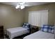 Bright bedroom featuring twin beds with blue plaid accents, complemented by a ceiling fan and natural light from the window at 266 Las Flores, Winter Haven, FL 33884