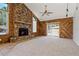 Living room boasting a grand stone fireplace, ceiling fan, carpet flooring, and natural light at 3022 Lantana Rd, Auburndale, FL 33823