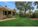 Manicured backyard featuring lush green grass, mature landscaping, and a view of the home's exterior at 3158 Beauchamp Ct, Winter Haven, FL 33884