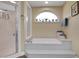 Bright bathroom featuring a large soaking tub with tiled platform and an arched window with plants at 3158 Beauchamp Ct, Winter Haven, FL 33884