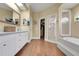 Bright bathroom featuring wood-look floors, double vanity, walk-in shower, and separate soaking tub at 3158 Beauchamp Ct, Winter Haven, FL 33884