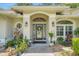 Inviting front entrance featuring decorative plants, a modern front door with sidelights, and stylish outdoor lighting at 3158 Beauchamp Ct, Winter Haven, FL 33884