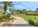 Well-manicured front yard with lush landscaping, a paved walkway, and mature palm trees at 3158 Beauchamp Ct, Winter Haven, FL 33884