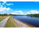 Scenic lake view with walking path, lush landscaping, and clear blue skies offering a serene outdoor experience at 3374 Waterlute Way, Lakeland, FL 33811