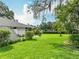 Expansive backyard featuring lush lawn, mature trees, and a charming white home exterior at 42 Grenewood Ln, Haines City, FL 33844