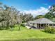 Expansive backyard featuring a lush lawn, mature trees, and a cozy patio area perfect for outdoor entertaining at 42 Grenewood Ln, Haines City, FL 33844